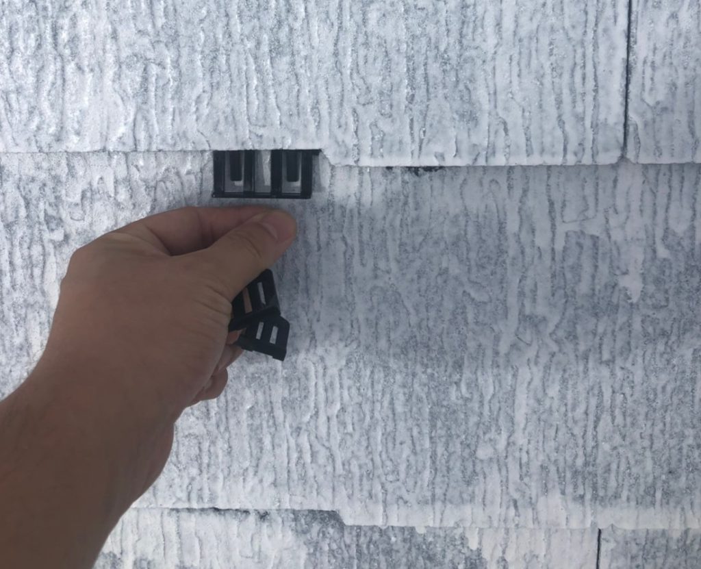 高圧洗浄、屋根の下塗りを行った後に、タスペーサーという縁切り用の部材を瓦の重なり部分に挿入します。